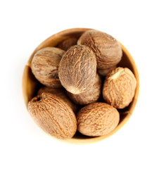 Nutmeg in wooden bowl, isolated on white