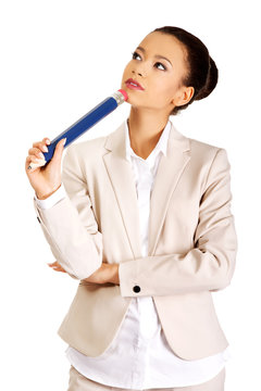 Thoughtful businesswoman with big pencil.