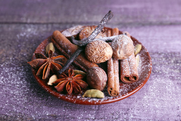 Spices in plate with powdered sugar on color wooden table background