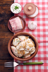 Tasty dumplings with fried onion in brown bowl, on wooden background
