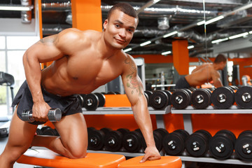 Fototapeta na wymiar Muscular man doing exercises with dumbbells in gym 