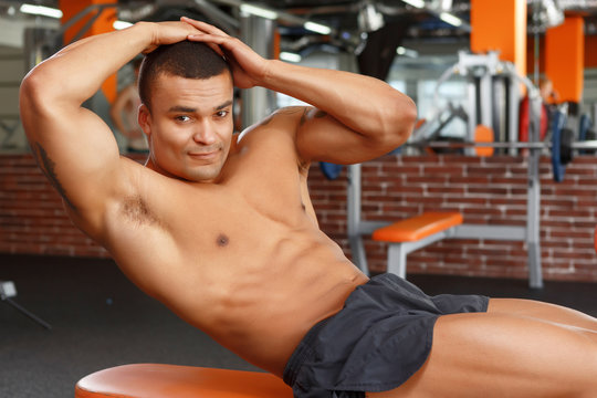 Young pleasant man doing abdominal crunches in gym