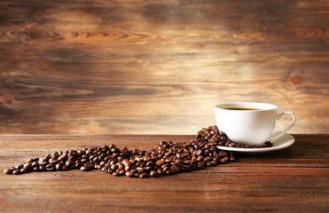 Cup of coffee with grains on wooden background