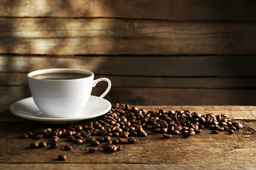 Cup of coffee with grains on wooden background