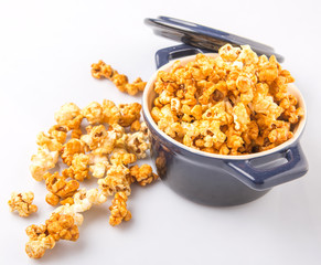 Caramel popcorn in blue pot over white background