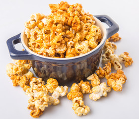 Caramel popcorn in blue pot over white background