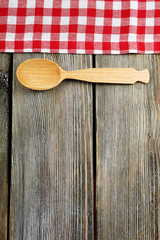 Checkered napkin with spoon on wooden table background
