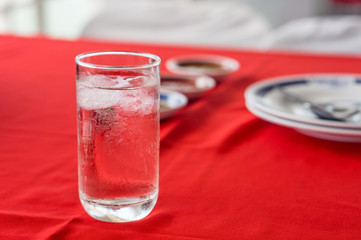 A glass of fresh water on a red table in restaurant
