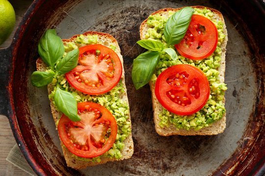 Vegan sandwich with avocado and vegetables on pan, close-up