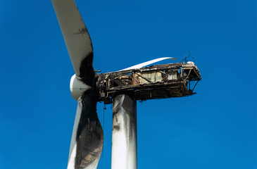 View of Burned wind turbine over blue sky.