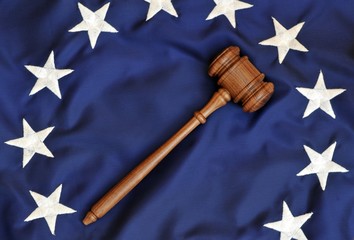 American Justice. A wooden judge's gavel atop stars from an old American flag.