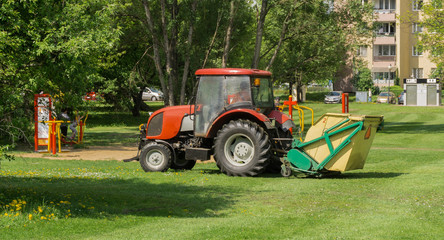 Tractor with trailer mowing grass 