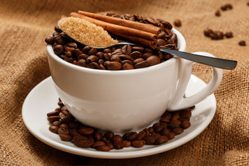 Cup filled with coffee beans and spoon with brown sugar