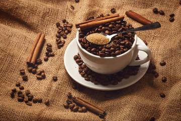 Cup filled with coffee beans and spoon with brown sugar