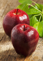 Red apples with water drops on a wooden table, selective focus