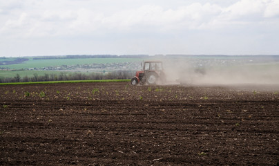 Украина, вспаханное поле и трактор в клубах пыли