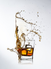 Whiskey drink with splash and ice cubes