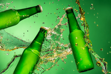 Bottles of beer with splash, on green background