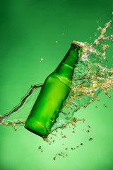 Bottle of beer with splash, on green background