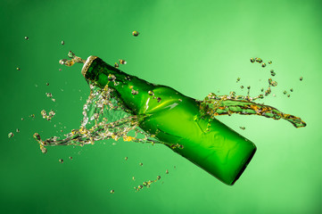 Bottle of beer with splash, on green background