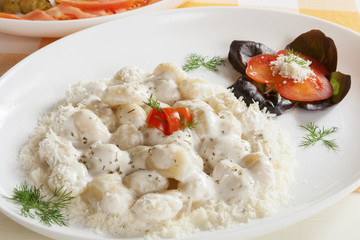 Servings of gnocchi with white truffle sauce with garnish.