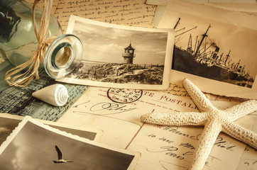 Still life with vintage beach photos, starfish, glass bottle with string tied to the neck on...