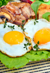 Bacon with sunny side up eggs served with toasts on a orange nap