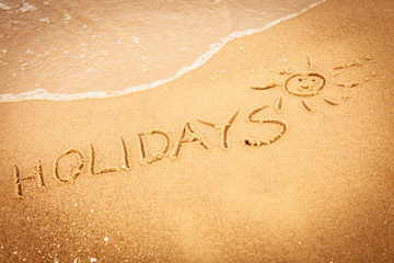 The word holidays written in the sand on a beach