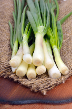 Green onions  on sacking and on a wooden board