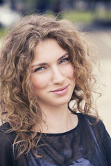 Naklejka premium Outdoors portrait of a beautiful girl with curly hair