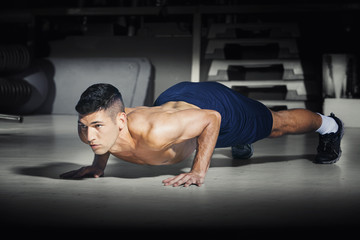 Muscular man doing push ups at gym
