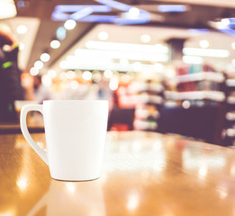 Vintage filter : White coffee cup on wood table at blur cafe bac