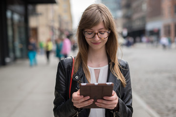 Young caucasian woman in city walking using tablet pc