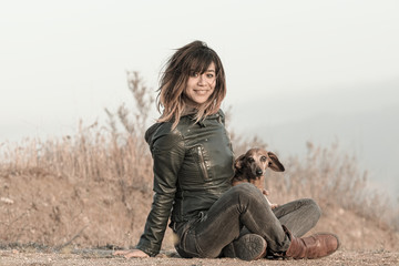 Seated woman with leather jacket and Dachshund
