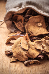 Dry mushrooms in sack on wooden table.