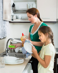 Girl helping mother washing dishes
