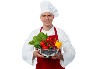 Male chef holding vegetables bowl