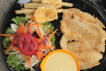 fish steaks and vegetable salad with french fries.
