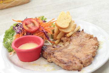steaks and vegetable salad with french fries.
