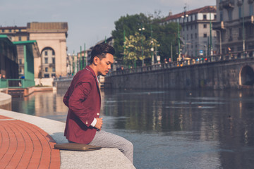Handsome Asian model sitting by an artificial basin