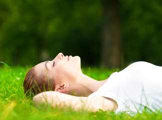 Young woman lying on grass and relaxing in park.