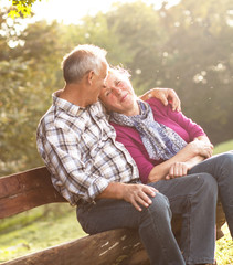 Smiling senior couple relaxing in park sitting on a bench.