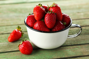Strawberries in cup on green wooden background