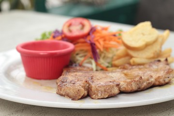 steaks and vegetable salad with french fries.