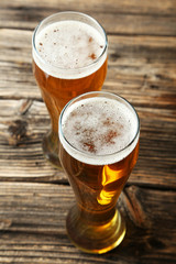 Two glass of beer on brown wooden background