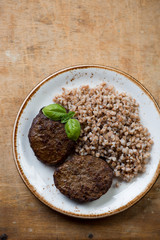Buckwheat and meat cutlets, rustic wooden surface, above view