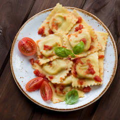 Above view of italian ravioli with tomato sauce and green basil