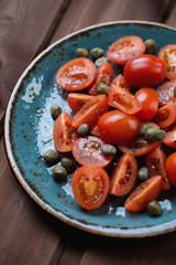 Sliced tomatoes with caper berries, sea salt and pepper, closeup