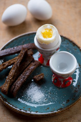 Breakfast soft-boiled eggs with breadsticks and salt, close-up