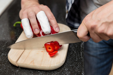 Mann schneidet mit verletzten Fingern Paprika